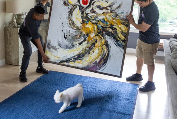 Boston movers moving large piece of art while a dog walks by